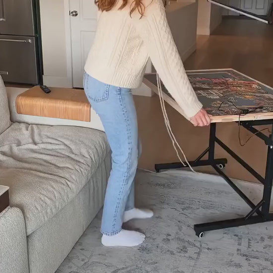 Woman tilting the PuzzleNest rolling puzzle table next to her couch
