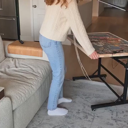 Woman tilting the PuzzleNest rolling puzzle table next to her couch