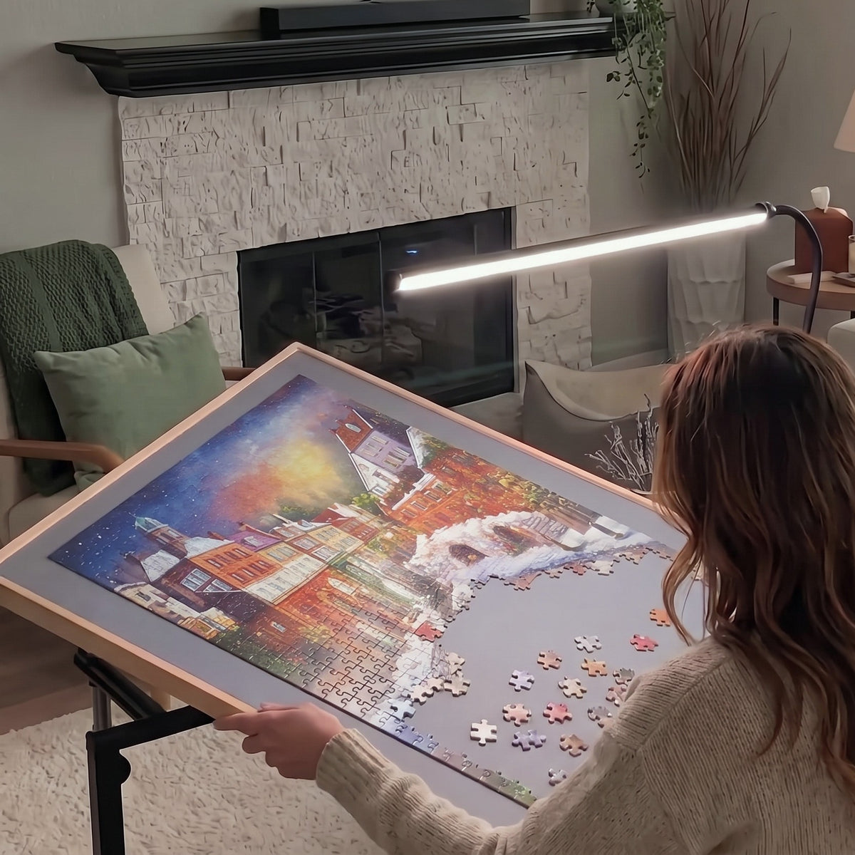 Woman puzzling on a tilted PuzzleNest table in front of the TV and fireplace